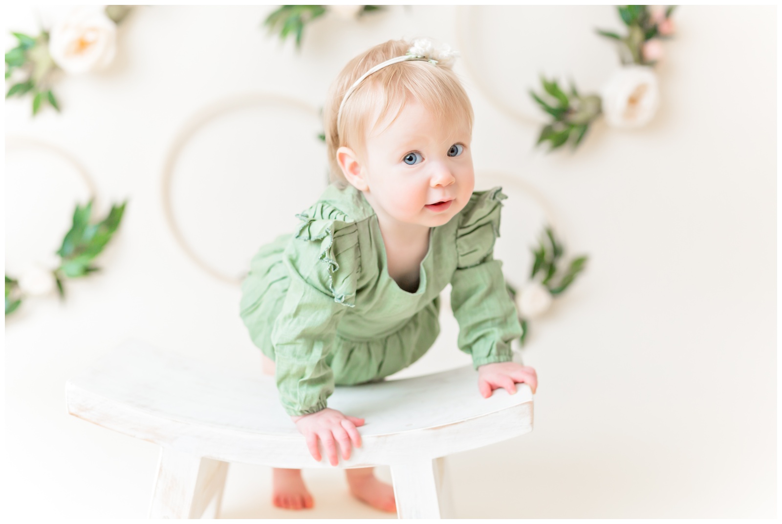 1 year old in green romper on stool, looking at camera, studio session